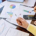 A close-up of businesspeople analyzing financial data and charts during a meeting.