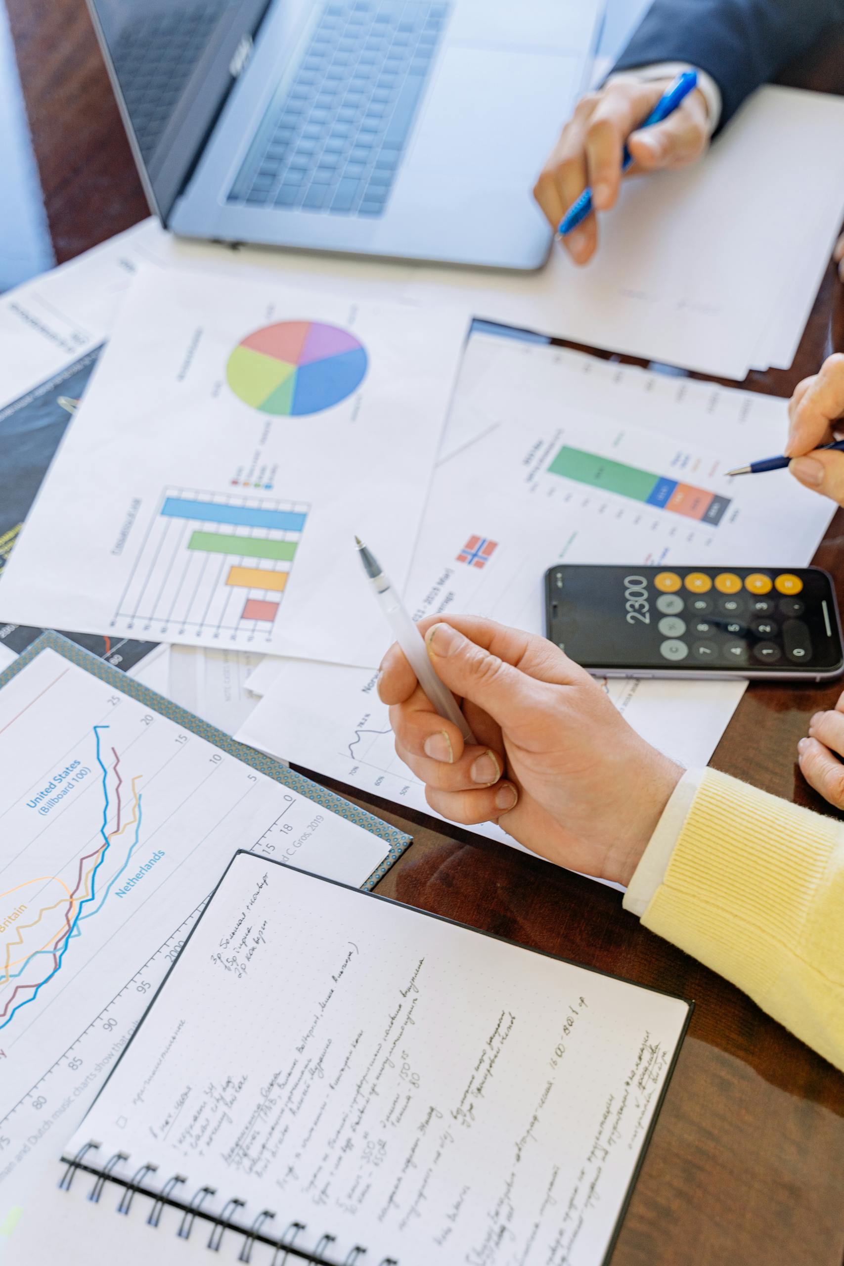 A close-up of businesspeople analyzing financial data and charts during a meeting.